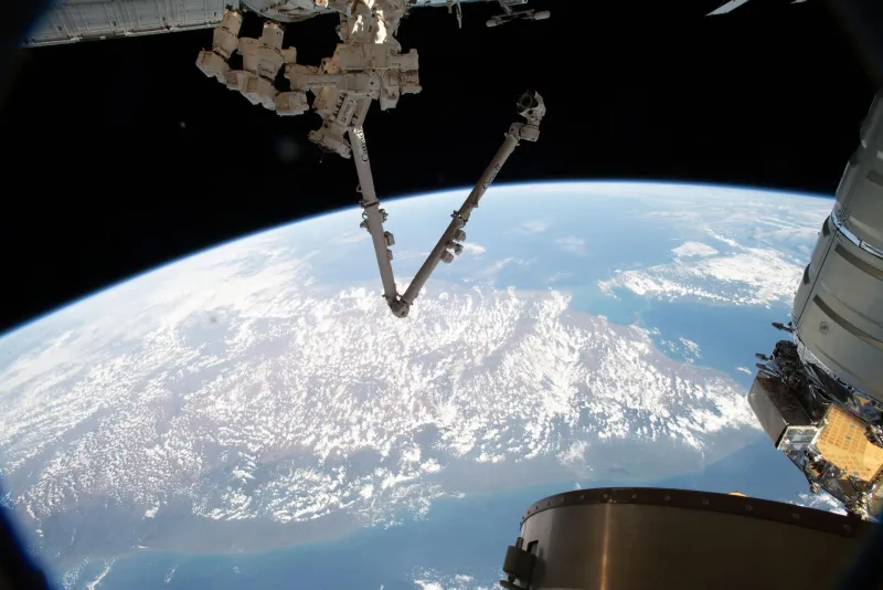 The space station's Canadarm2 robotic arm and Dextre robot above Earth (NASA)